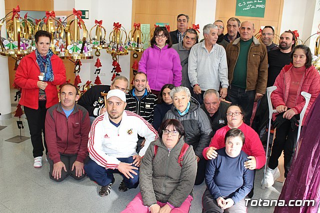 Usuarios de los centros de día para la discapacidad hacen entrega a la Asociación de Comerciantes de los adornos de Navidad que decorarán de forma uniforme los establecimientos adheridos a esta entidad