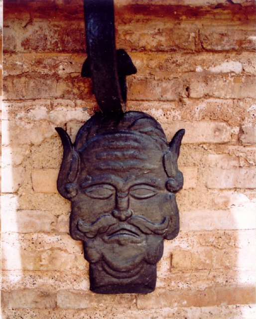 Mascarón que pende de la balconada de la iglesia de Santiago. Este rostro se asemeja al de un fauno de la mitología, espíritu clásico de la fertilidad agrícola que, con su poder, ejerce una benéfica ayuda al crecimiento de los cereales.