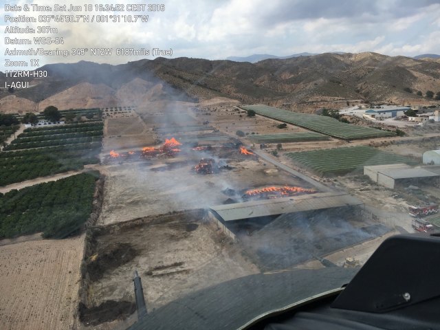 Helicóptero de la DGSCyE y bomberos del Consorcio trabajan en la extinción del incendio en una granja en Totana